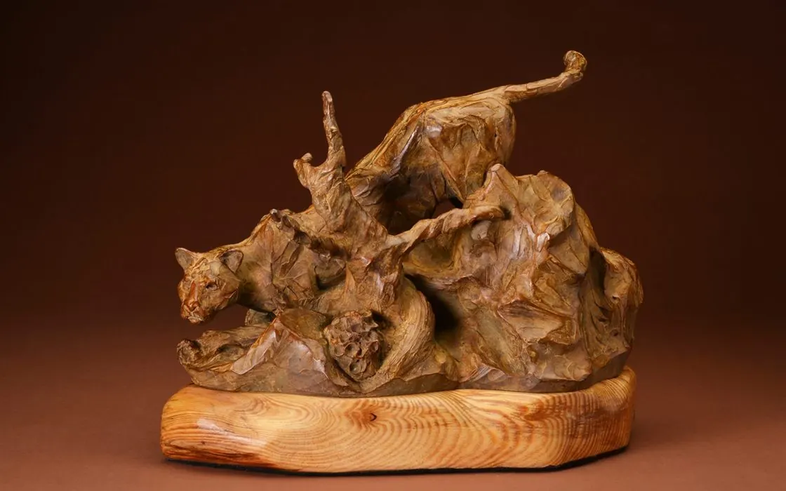 A bronze mountain lion sculpture by Scott Mortensen, shown mid-stride.